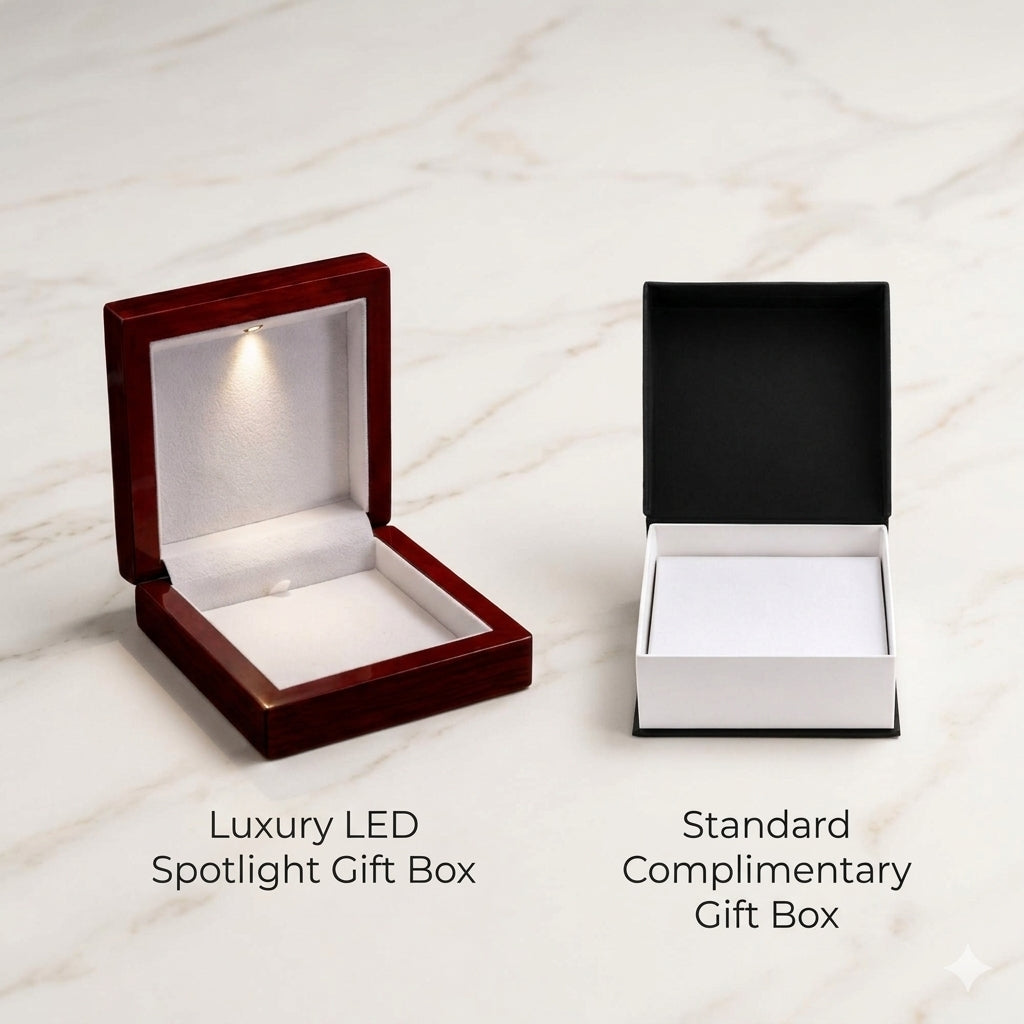 An elegant, top-down product display showcasing two empty jewelry packaging options side by side on a bright, polished white marble surface. On the left is an open mahogany-style wooden box illuminated by a built-in LED spotlight, labeled underneath with clean text as "Luxury LED Spotlight Gift Box". On the right is an open two-tone black and white cardboard box, labeled underneath as "Standard Complimentary Gift Box".