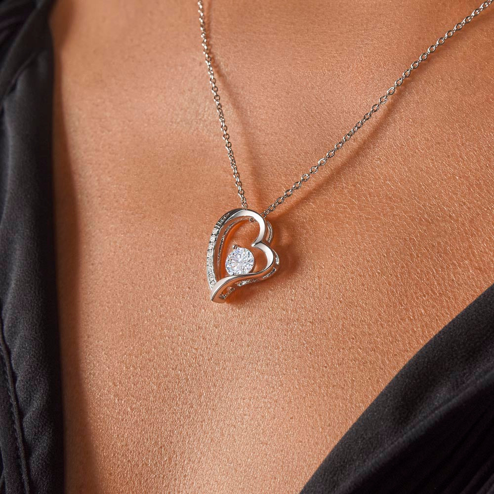 Close-up of a woman in a black blouse wearing a 14k white gold over stainless steel heart pendant necklace accented with sparkling cubic zirconia crystals.