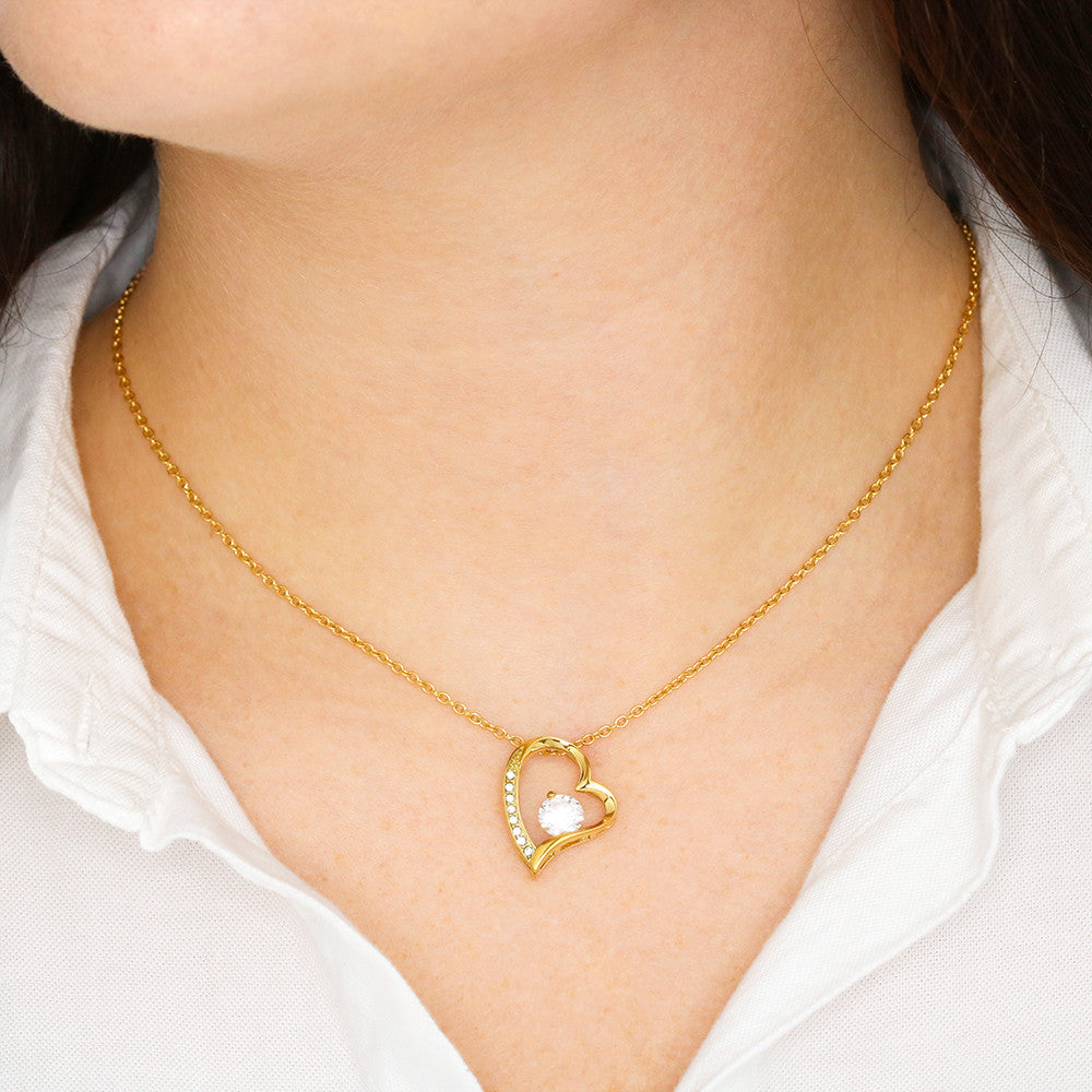 Close-up of a woman in a white blouse wearing a 18k gold over stainless steel heart pendant necklace accented with sparkling cubic zirconia crystals.