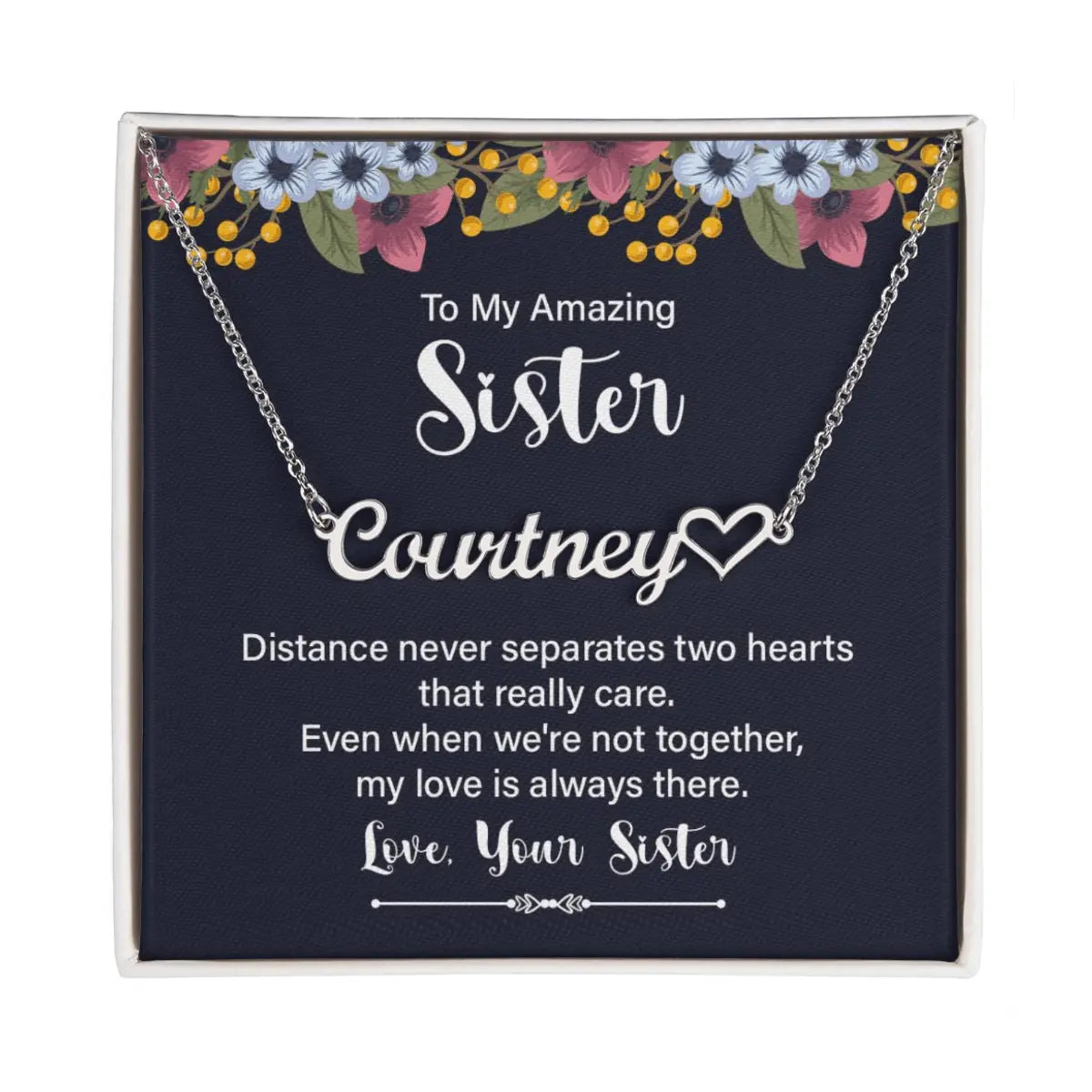 Personalized silver necklace with a heart-shaped nameplate, presented in a square gift box with a navy card featuring floral accents and a sentimental message for a sister.