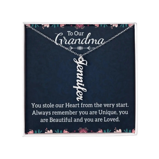 A personalized silver nameplate necklace displayed on a dark navy gift card with floral accents and a sentimental message for 'Grandma'.