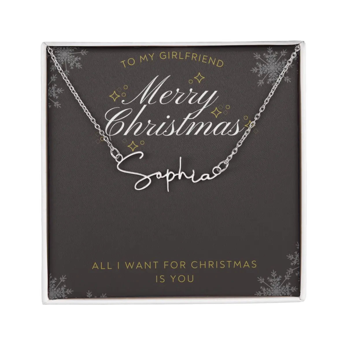 A personalized silver necklace with a script nameplate reading 'Sophia', presented on a dark gray square gift card with gold and white holiday text and snowflake designs. The card is addressed 'TO MY GIRLFRIEND' and reads 'Merry Christmas Sophia' and 'ALL I WANT FOR CHRISTMAS IS YOU'.