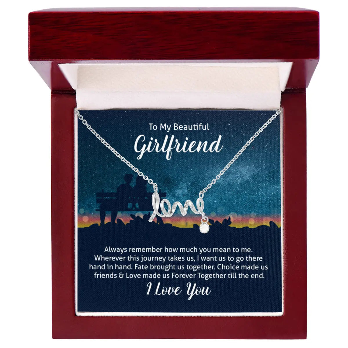 A silver necklace with a 'love' script pendant and a small heart charm, presented inside a dark red wooden gift box. The necklace is displayed on a printed card that reads 'To My Beautiful Girlfriend' and includes a romantic message at the bottom.
