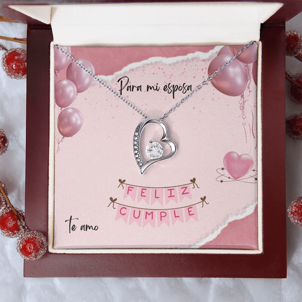 Collar plateado con dije de corazón y cristal brillante, presentado en una caja de madera de caoba abierta con una tarjeta de cumpleaños rosa para esposa.
