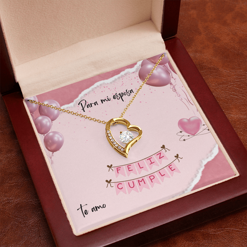 Collar de oro con dije de corazón y cristal brillante, presentado en una caja de madera de caoba abierta con una tarjeta de cumpleaños rosa para esposa.
