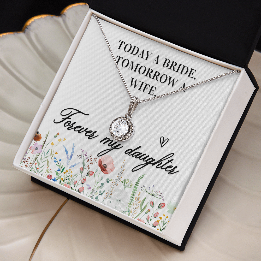 A bridal shower gift card featuring a silver necklace with a clear round gemstone pendant. The card has a white background with black text reading 'TODAY A BRIDE, TOMORROW A WIFE, Forever my daughter' and a watercolor floral border at the bottom, sitting on a cream colored shell shaped jewelry dish with gold trim.
