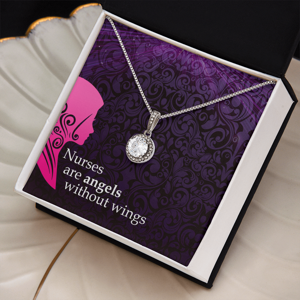 A silver chain necklace with a round, halo-set crystal pendant is presented inside an open white jewelry box with a dark border. The necklace rests against a decorative purple card with a damask pattern, a pink nurse silhouette, and the white text, "Nurses are angels without wings."
