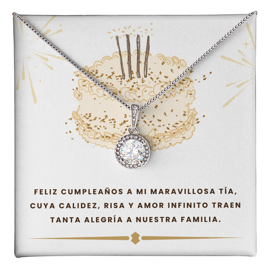 Un collar plateado con un dije circular de cristal brillante, presentado sobre una tarjeta de regalo blanca. El fondo de la tarjeta muestra la ilustración de un pastel de cumpleaños dorado con tres velas y destellos. En la parte inferior, lleva el texto impreso en letras oscuras: "FELIZ CUMPLEAÑOS A MI MARAVILLOSA TÍA, CUYA CALIDEZ, RISA Y AMOR INFINITO TRAEN TANTA ALEGRÍA A NUESTRA FAMILIA".
