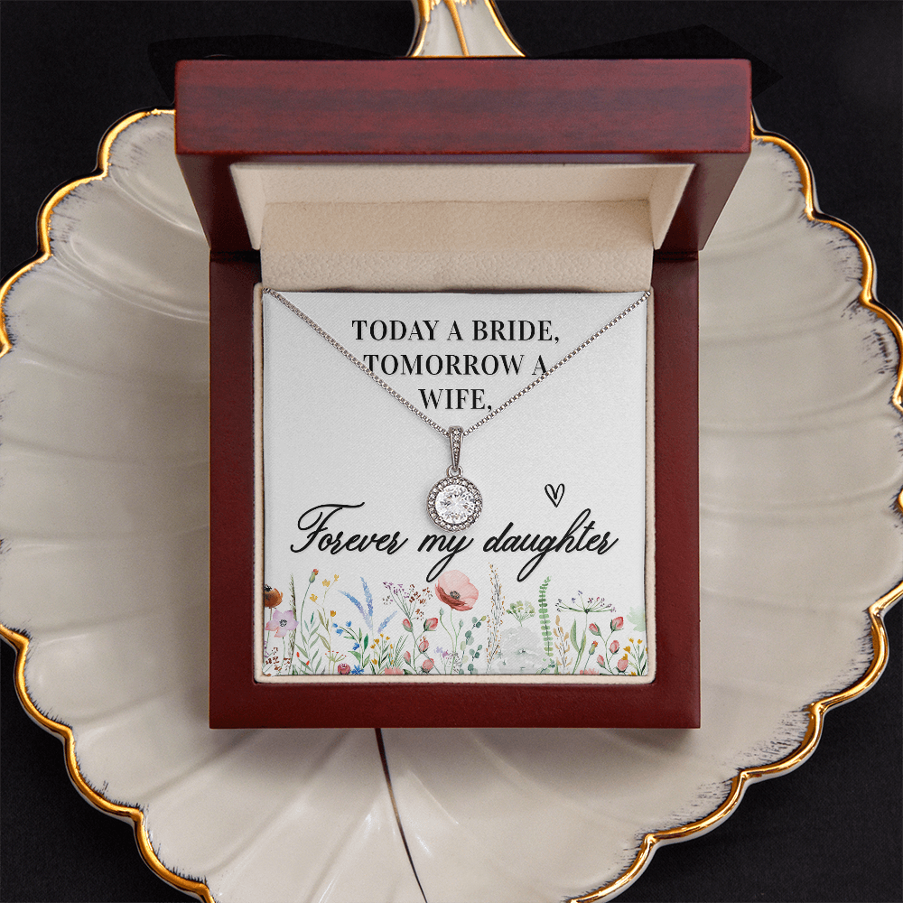 A bridal shower gift card featuring a silver necklace with a clear round gemstone pendant. The card has a white background with black text reading 'TODAY A BRIDE, TOMORROW A WIFE, Forever my daughter' and a watercolor floral border at the bottom, sitting on a cream colored shell shaped jewelry dish with gold trim.