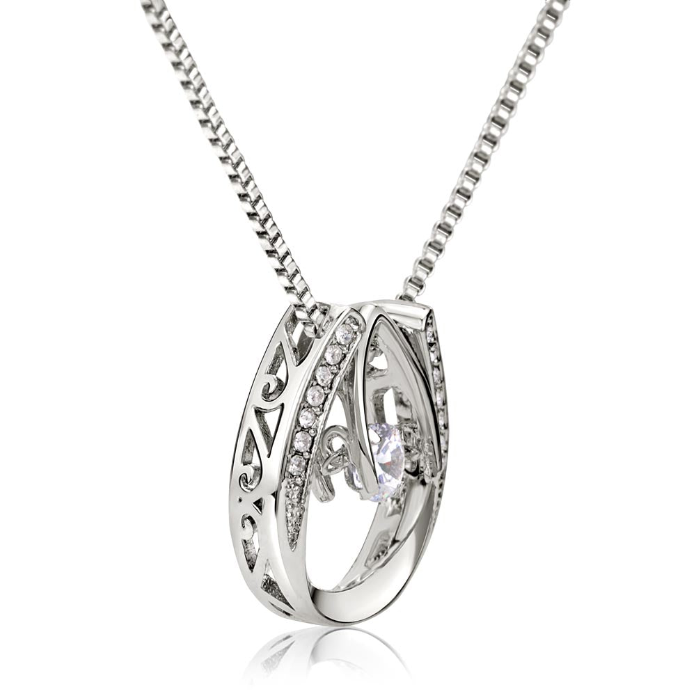 Extreme close-up shot of a silver horseshoe pendant necklace featuring an outer horseshoe ring lined with small stones and a large dancing cubic zirconia crystal.