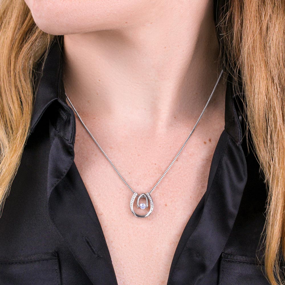 Close up of a long-haired women in a black shirt wearing the silver lucky horseshoe necklace.