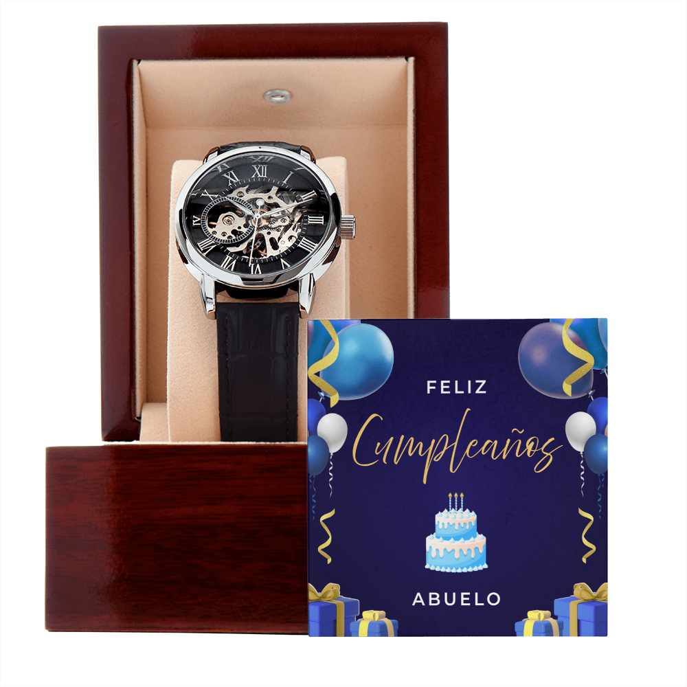 Reloj esqueleto de lujo para hombre con correa negra, presentado dentro de una caja de madera de caoba abierta con una tarjeta de feliz cumpleaños para abuelo de fondo.