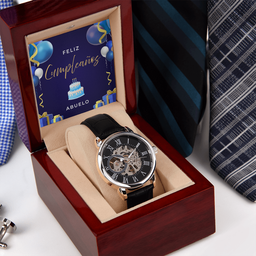 Reloj esqueleto automático para hombre en caja de madera de caoba abierta con tarjeta de "Feliz Cumpleaños Abuelo", posado junto a elegantes corbatas de vestir.