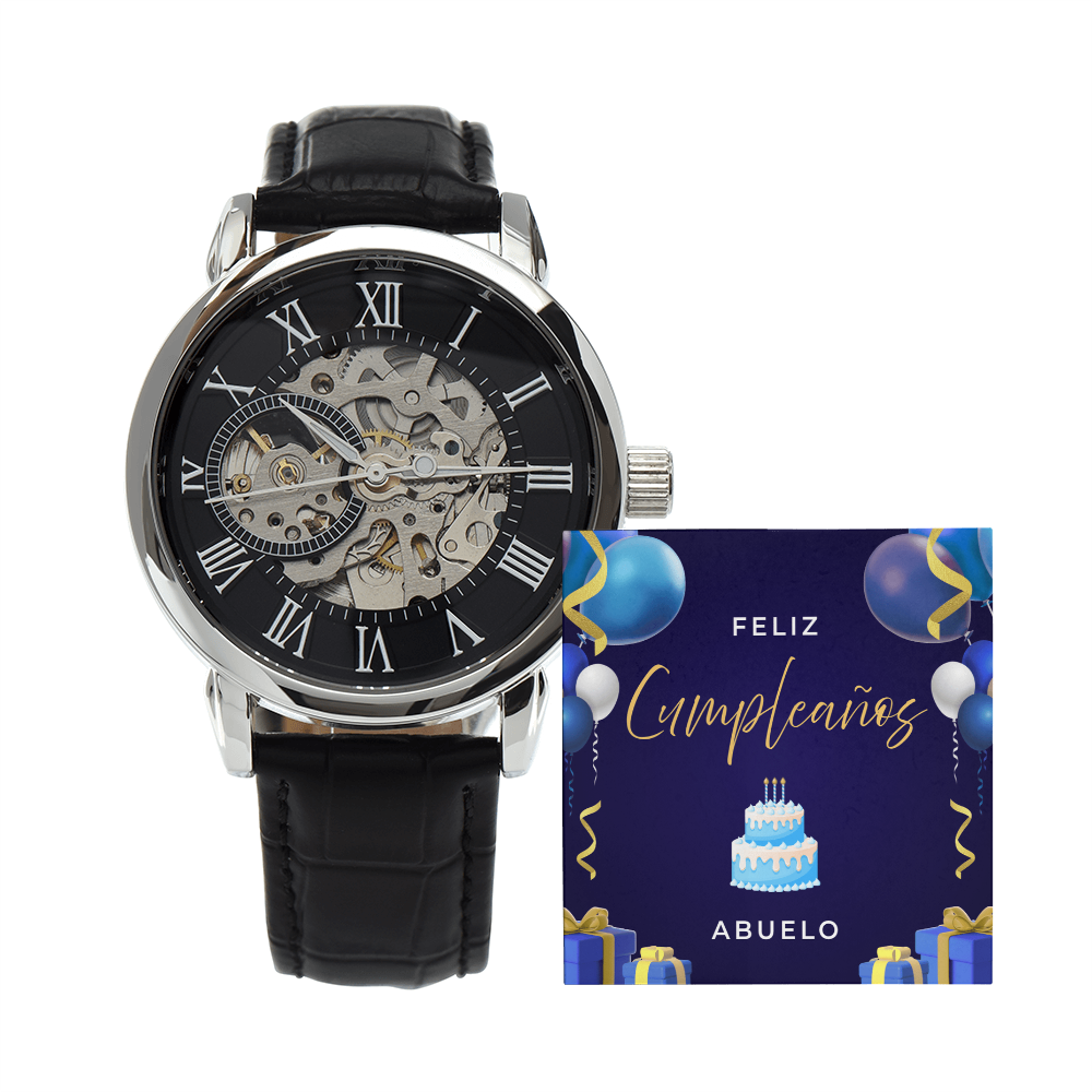 Reloj esqueleto de lujo para hombre con correa de cuero negro junto a una tarjeta de cumpleaños azul que dice "¡FELIZ CUMPLEAÑOS! abuelo" sobre un fondo blanco.