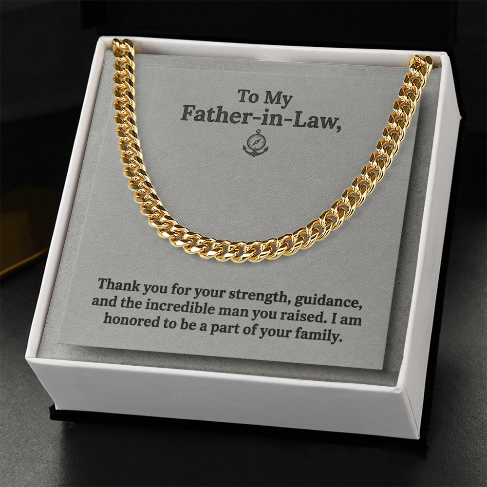 A gold-toned men's Cuban link chain necklace presented inside a square white gift box against a grey jewelry card. The card features an anchor and compass icon at the top center with the printed text: "To My Father-in-Law, Thank you for your strength, guidance, and the incredible man you raised. I am honored to be a part of your family." The gift box lays on a sold black wooden background.