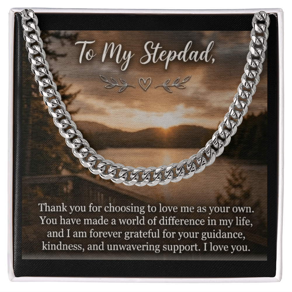 The card displays a scenic lakeside landscape at sunset or sunrise with dense pine trees lining the shores under a cloudy sky. At the top, the elegant script text reads, "To My Stepdad," adorned with a small heart and leaf flourishes underneath. The bottom half of the card features a heartfelt paragraph printed in a clean, white serif font. A silver men's Cuban link chain rests on the image.