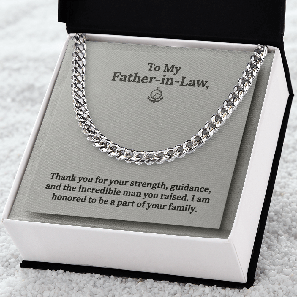 A silver-toned men's Cuban link chain necklace presented inside a square white gift box against a grey jewelry card. The card features an anchor and compass icon at the top center with the printed text: "To My Father-in-Law, Thank you for your strength, guidance, and the incredible man you raised. I am honored to be a part of your family." The gift box lays on a white towel like fabric.