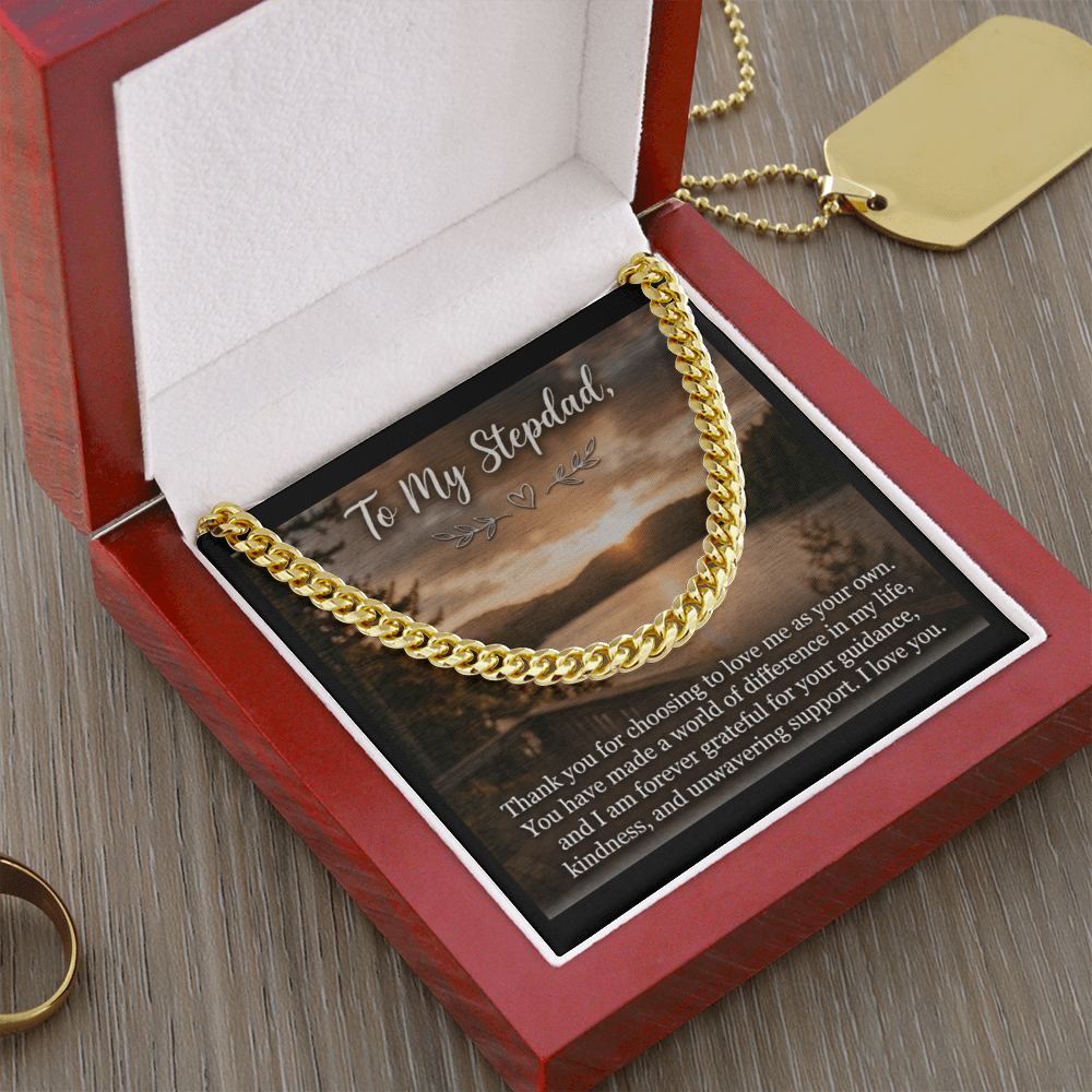 A polished men's gold Cuban link chain necklace resting inside an opened, luxury mahogany-style wooden gift box with a soft white interior.
The chain is elegantly draped across a square message card that features a scenic lakeside sunset landscape background. At the top of the insert card, stylized cursive text reads "To My Stepdad,".