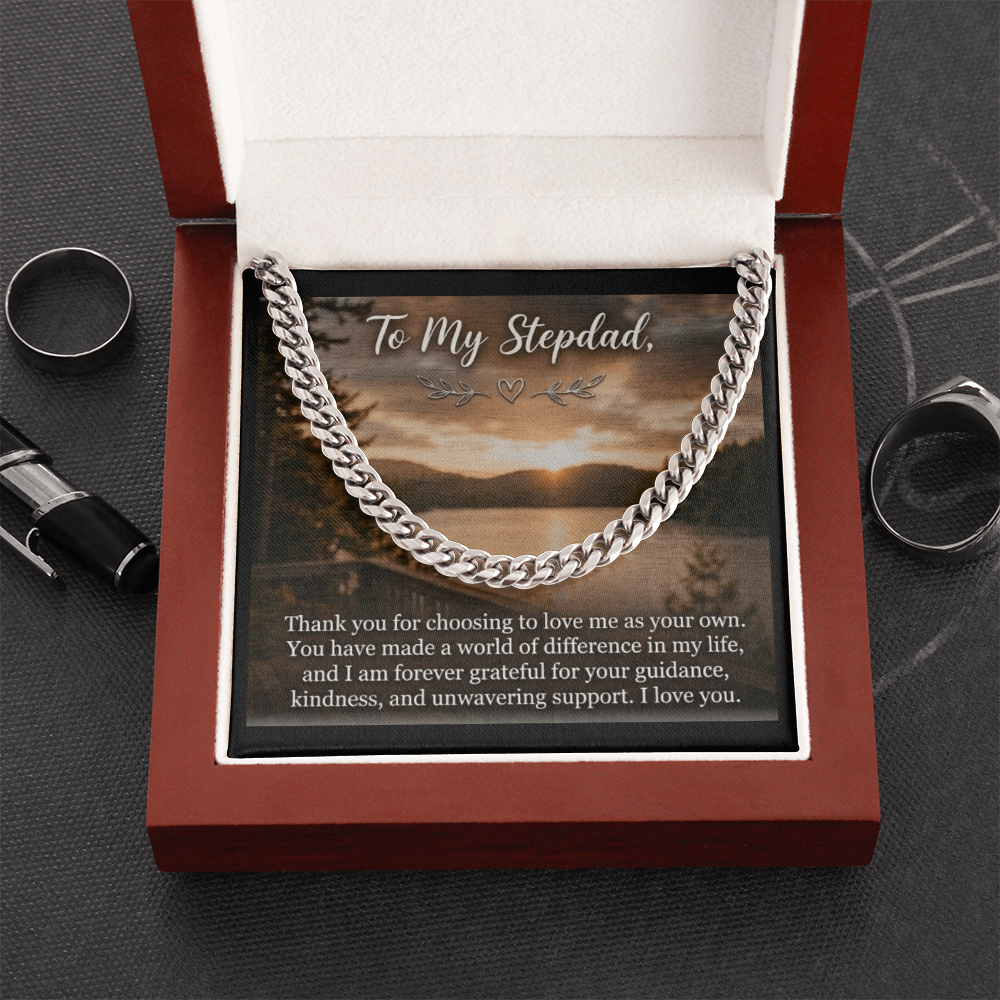 A polished men's silver Cuban link chain necklace resting inside an opened, luxury mahogany-style wooden gift box with a soft white interior.
The chain is elegantly draped across a square message card that features a scenic lakeside sunset landscape background. At the top of the insert card, stylized cursive text reads "To My Stepdad,".