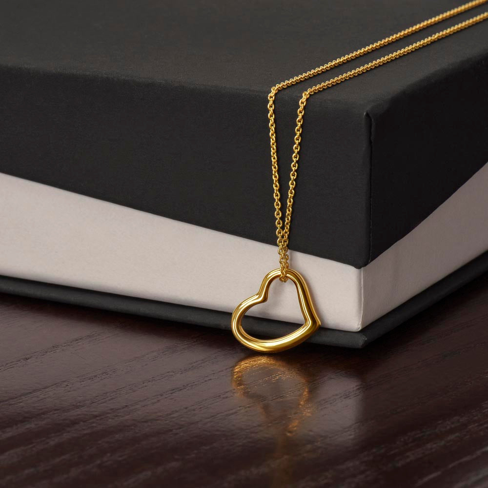 Close-up of a model wearing a delicate 18k gold chain necklace with an open heart pendant to show where it sits on the neckline.