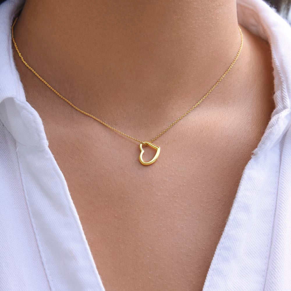 A model wearing a delicate 18k gold open heart necklace with a white collared shirt, showcasing how the pendant rests on the neckline.