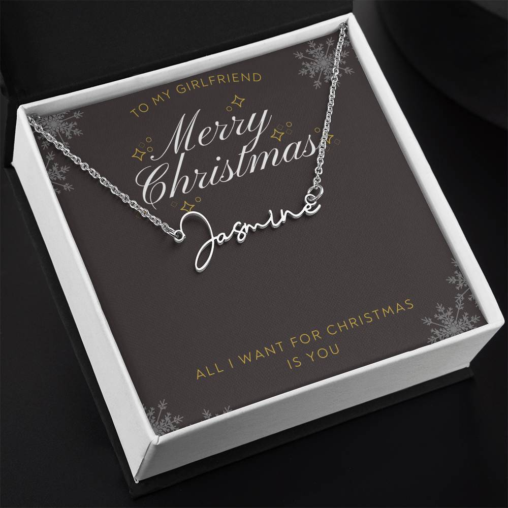 A personalized silver necklace with a script nameplate reading 'Sophia', presented on a dark gray square gift card with gold and white holiday text and snowflake designs. The card is addressed 'TO MY GIRLFRIEND' and reads 'Merry Christmas Sophia' and 'ALL I WANT FOR CHRISTMAS IS YOU' in a white gift box.
