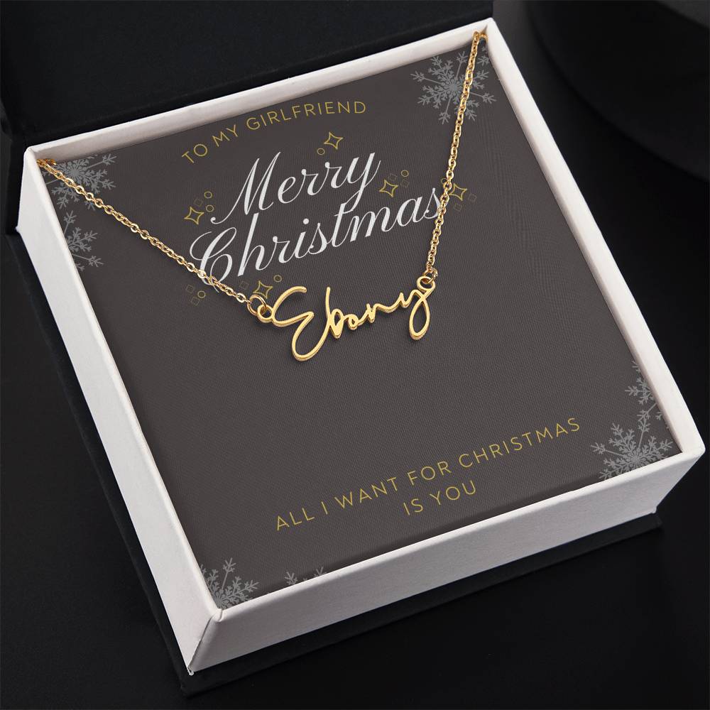 A personalized gold necklace with a script nameplate reading 'Sophia', presented on a dark gray square gift card with gold and white holiday text and snowflake designs. The card is addressed 'TO MY GIRLFRIEND' and reads 'Merry Christmas Sophia' and 'ALL I WANT FOR CHRISTMAS IS YOU'.