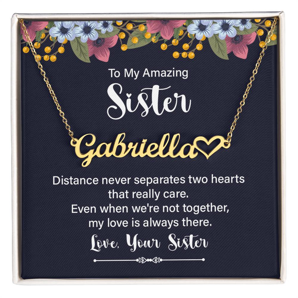 Personalized gold necklace with a heart-shaped nameplate, presented in a square gift box with a navy card featuring floral accents and a sentimental message for a sister.