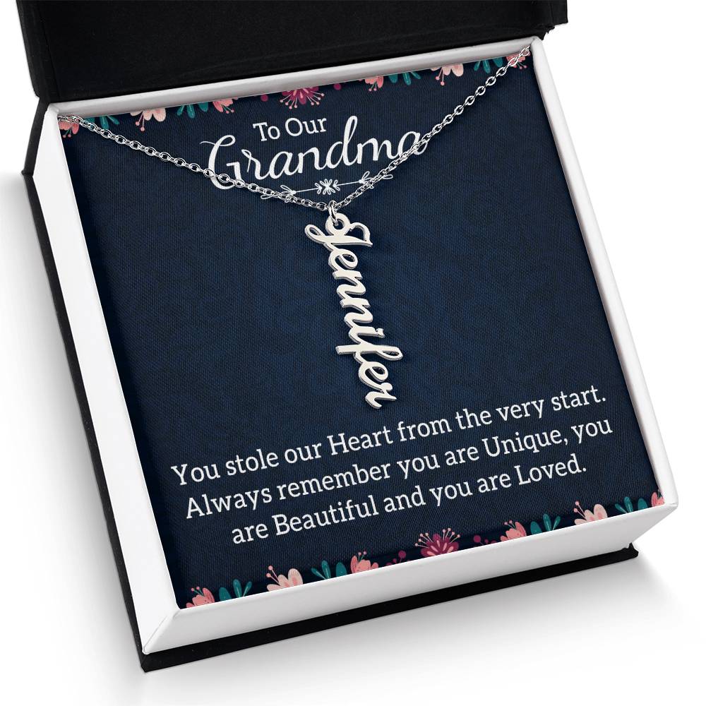 A personalized silver nameplate necklace displayed on a dark navy gift card with floral accents and a sentimental message for 'Grandma', in a black and white gift box.