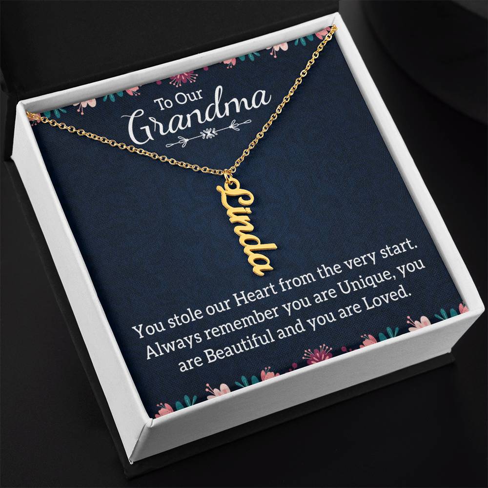 A personalized gold nameplate necklace displayed on a dark navy gift card with floral accents and a sentimental message for 'Grandma'.