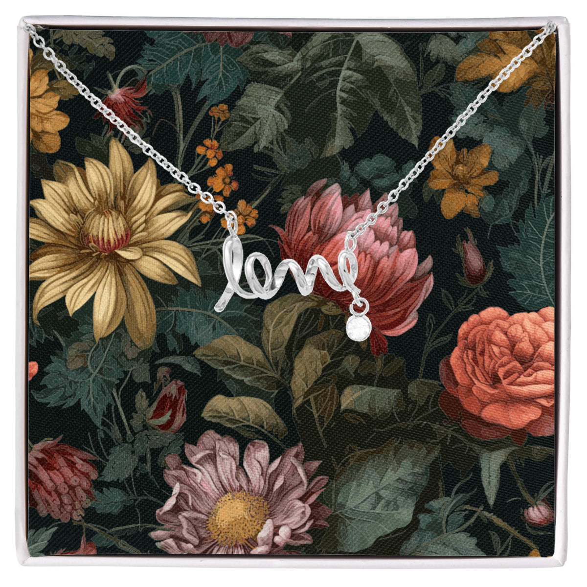 A silver script "love" necklace with a small dangling round crystal charm, displayed inside a white gift box against a dark floral backing card featuring vintage-style yellow, pink, and orange flowers.