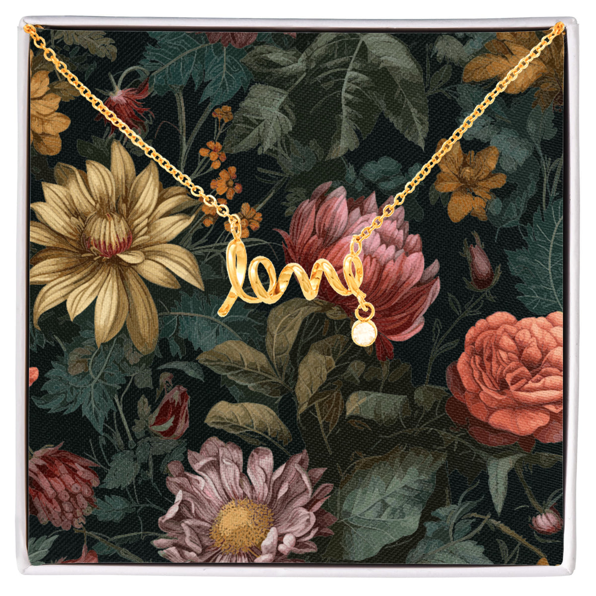 A gold script "love" necklace with a small dangling round crystal charm, displayed inside a white gift box against a dark floral backing card featuring vintage-style yellow, pink, and orange flowers.