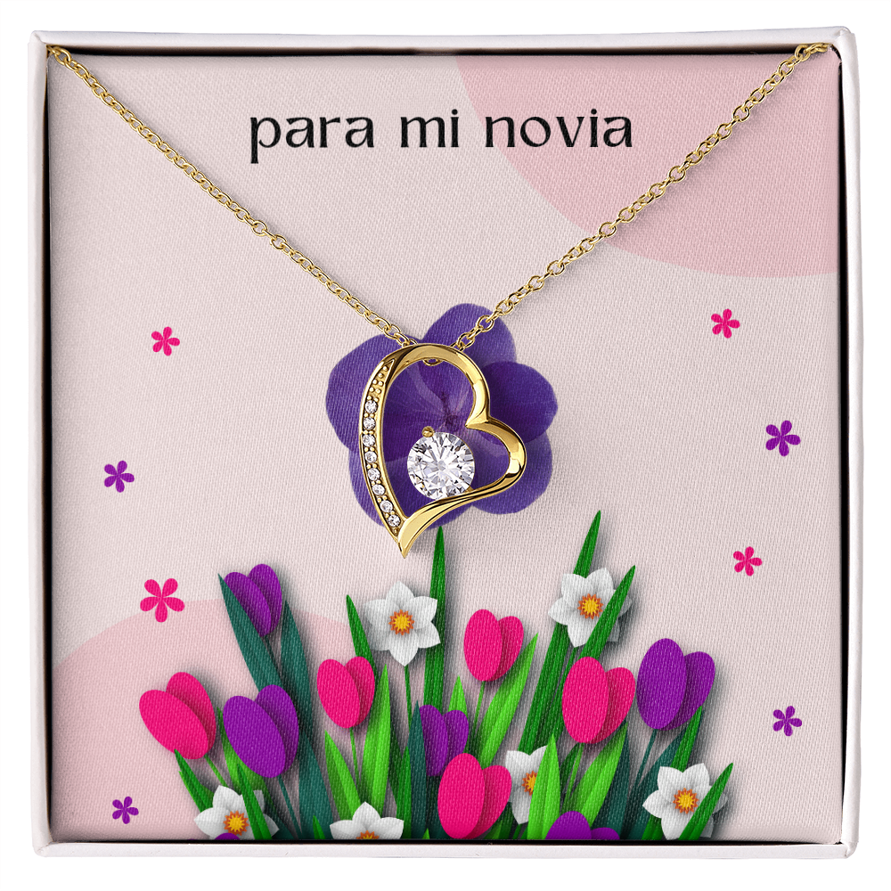 Collar de oro con dije de corazón y cristal brillante sobre una tarjeta de regalo floral rosa que dice "para mi novia" en letras minúsculas.