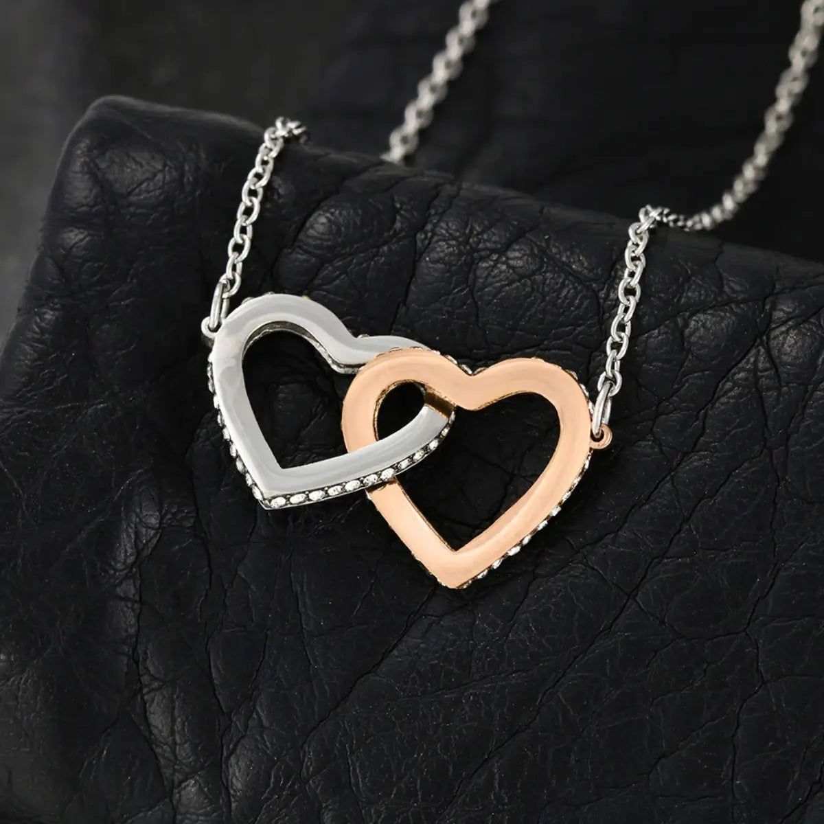 Necklace with interlocking heart pendants on a black textured surface