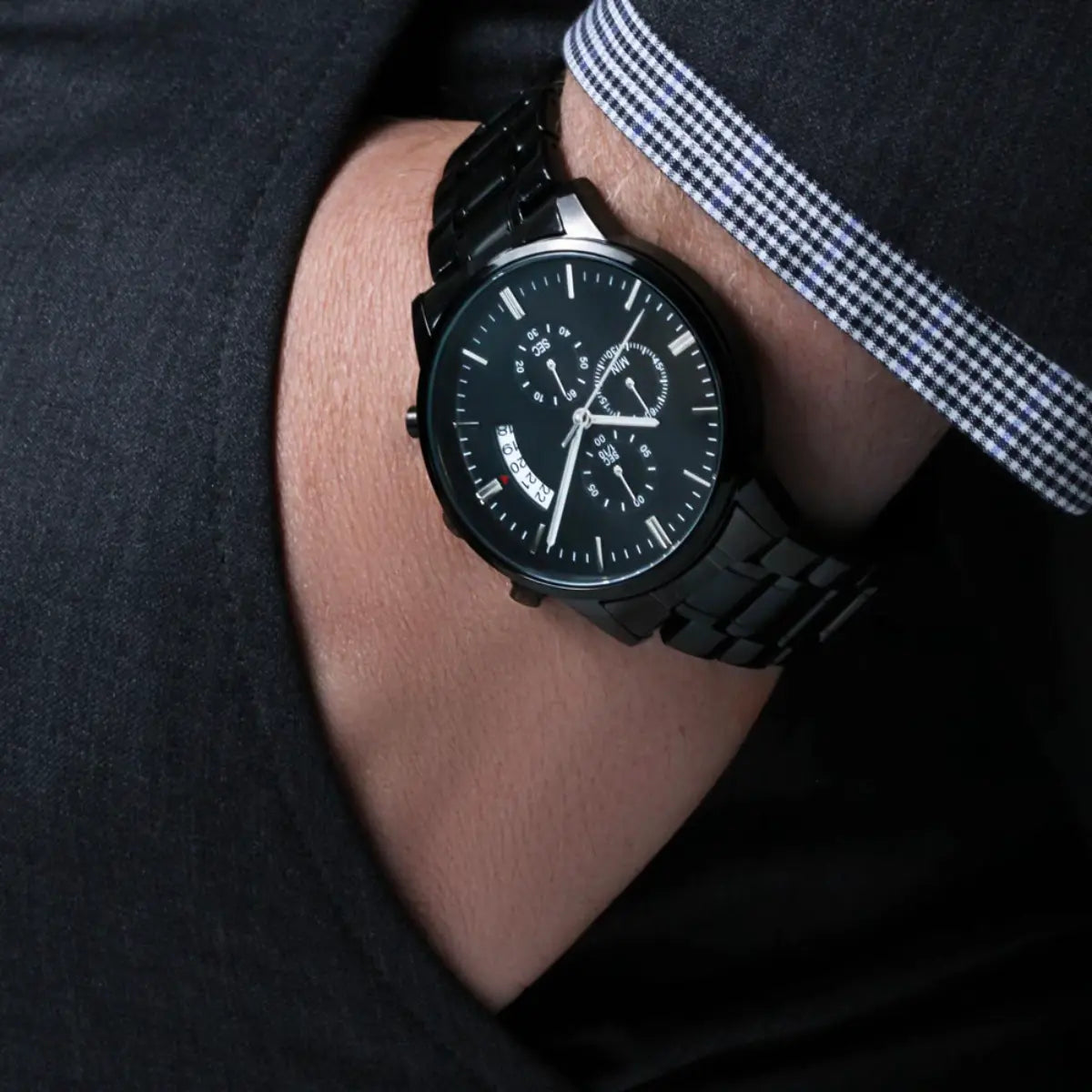 Black wristwatch on a person's wrist with a dark background