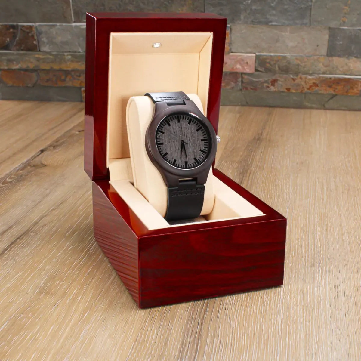 Brown wooden watch in a wooden display box on a wooden floor with stone wall background
