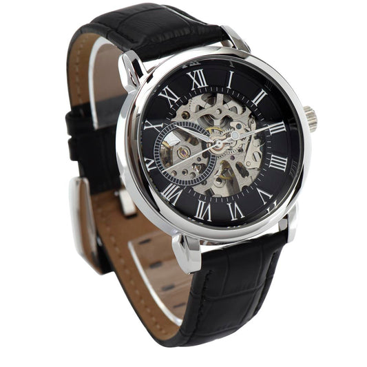 A close-up of a silver and black luxury skeleton watch on display.