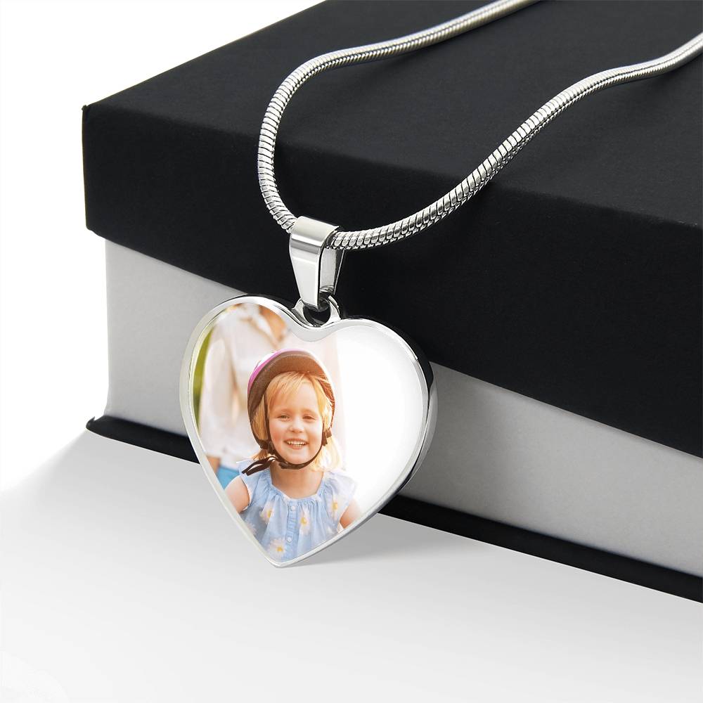 Custom heart picture necklace in silver resting against a black and white luxury jewelry gift box, showcasing a personalized family photo pendant with a snake chain.