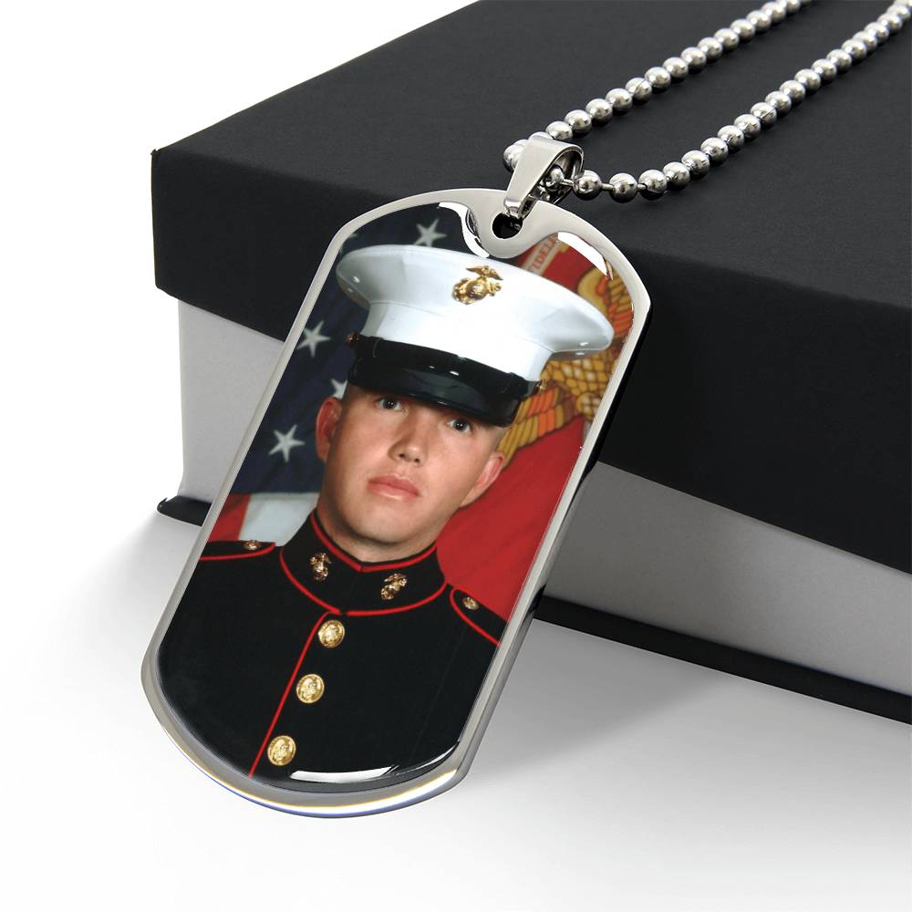Custom photo silver dog tag necklace with a silver ball chain, showing a portrait of a U.S. Marine, draped over a black and white gift box.