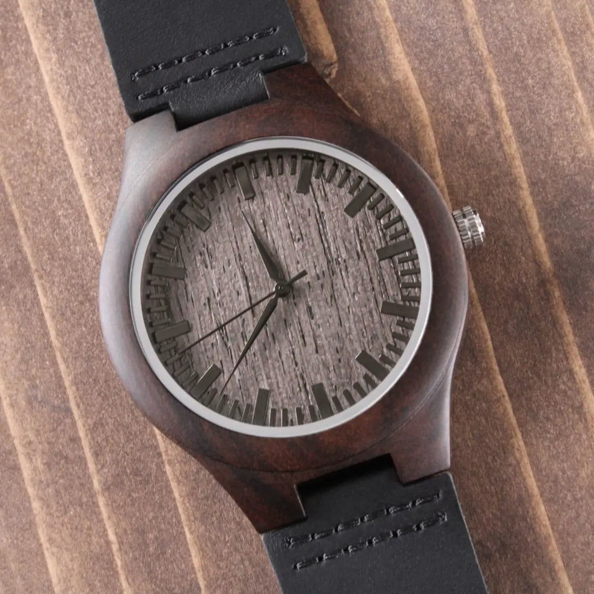 A wristwatch with a dark brown wooden case, a woodgrain-textured dial, and a black leather strap, shown on a wood-grain background.