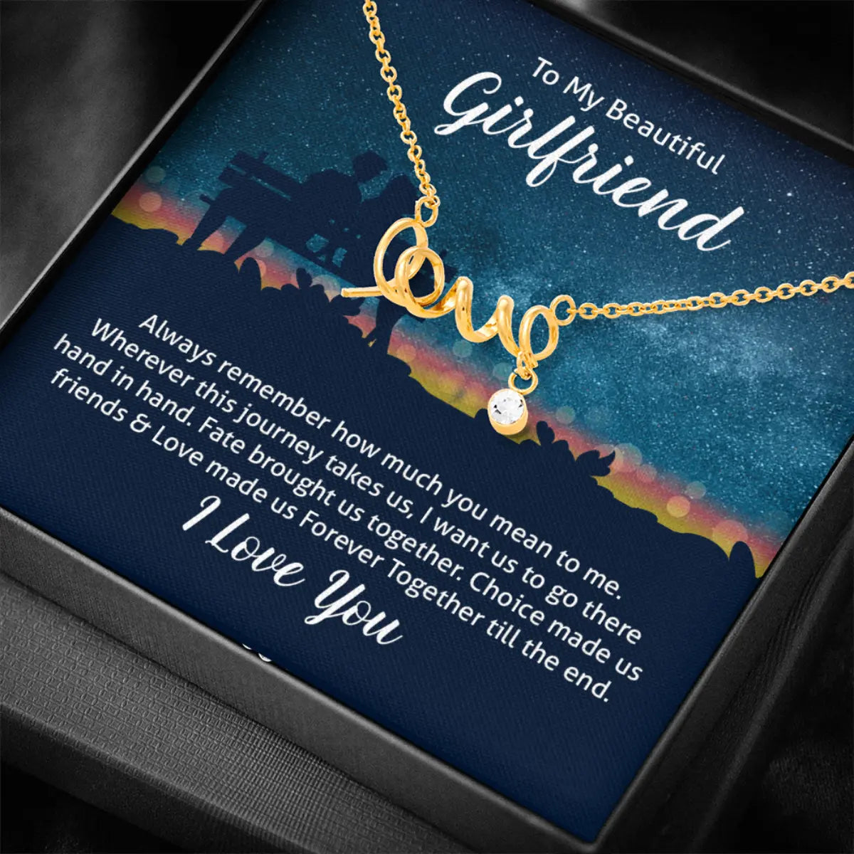 A gold necklace with a 'Love' pendant and a small heart charm, presented on a printed gift box insert addressed 'To My Beautiful Girlfriend' with romantic text and a starry night sky design.