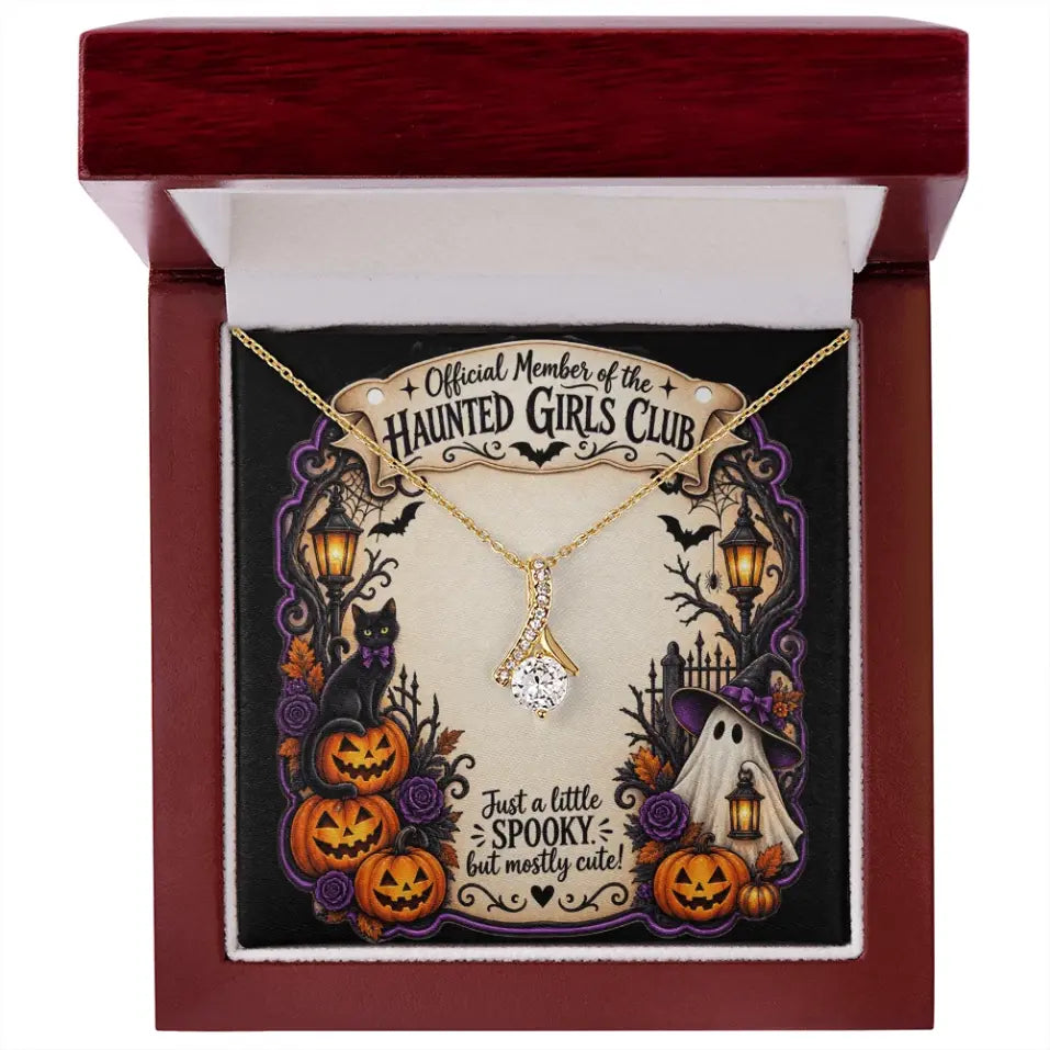 A gold necklace with a diamond-like pendant displayed inside an open dark red gift box. The necklace is mounted on a Halloween-themed printed card that reads 'Official Member of the Haunted Girls Club' and 'Just a little spooky, but mostly cute!'.