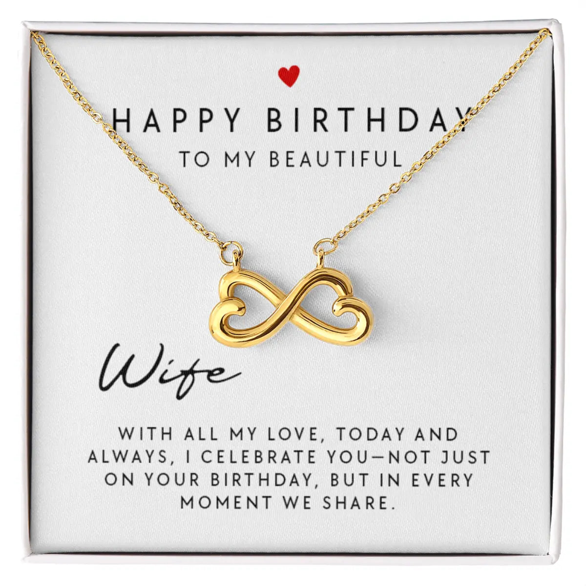 A gold infinity heart pendant necklace presented on a white gift box with a printed birthday message for a wife.