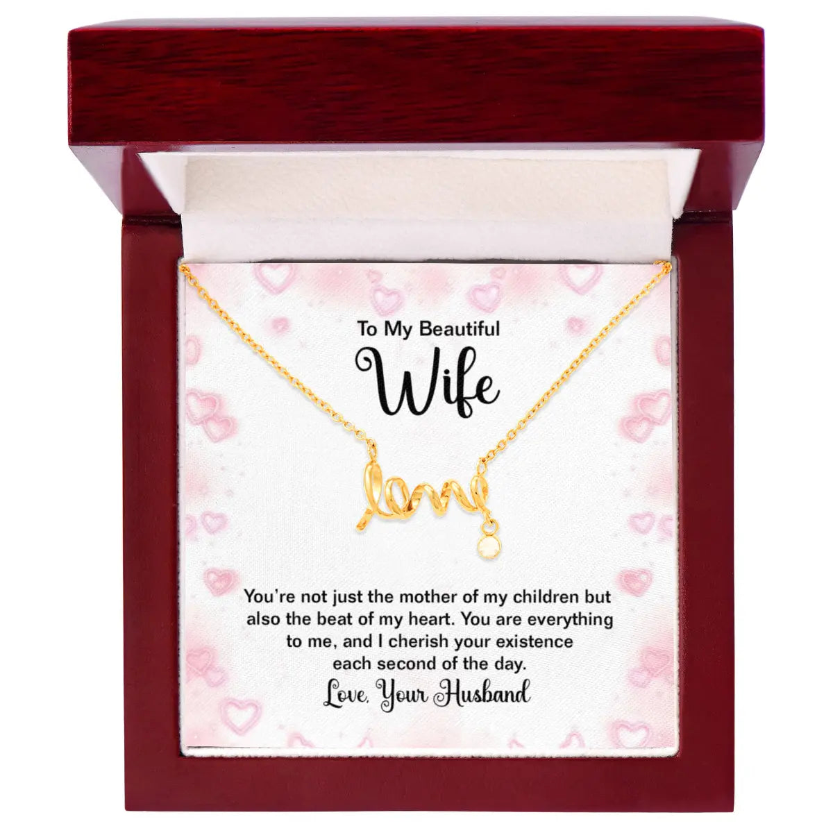 A gold necklace with a 'love' initial pendant is presented in an open dark red wooden gift box with a white insert card addressed to a wife, featuring a romantic quote.