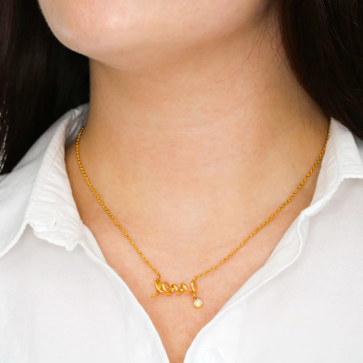 Gold necklace with a pendant on a person wearing a white shirt