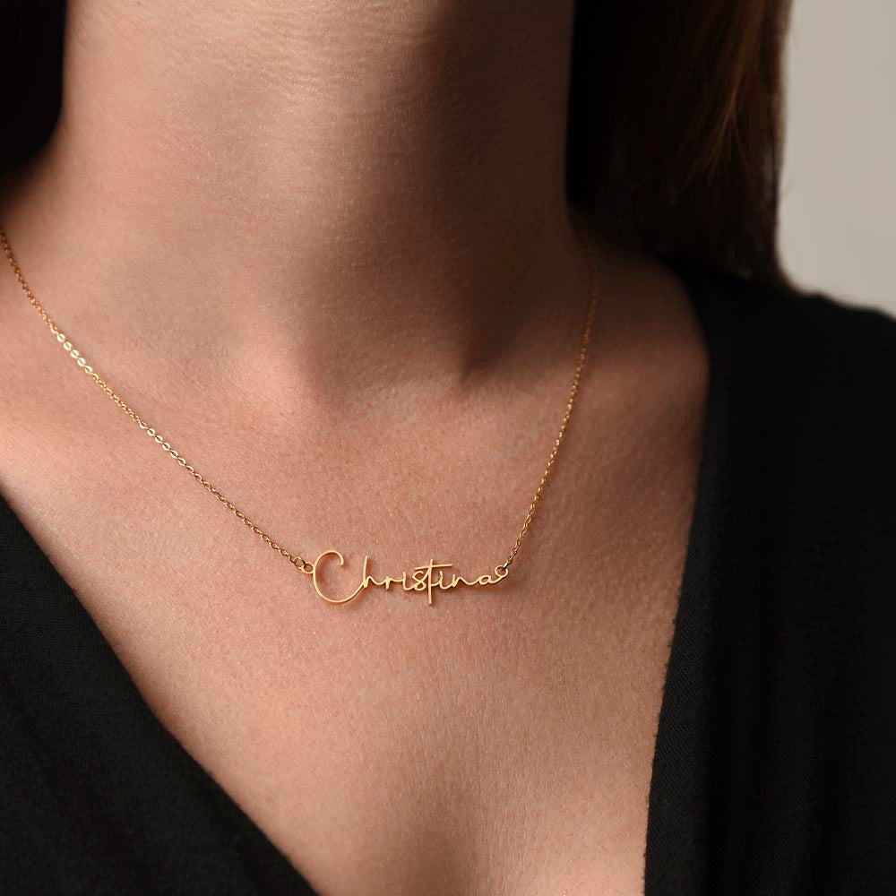 Woman in a black shirt wearing a gold personalized signature style name necklace to show scale and length.