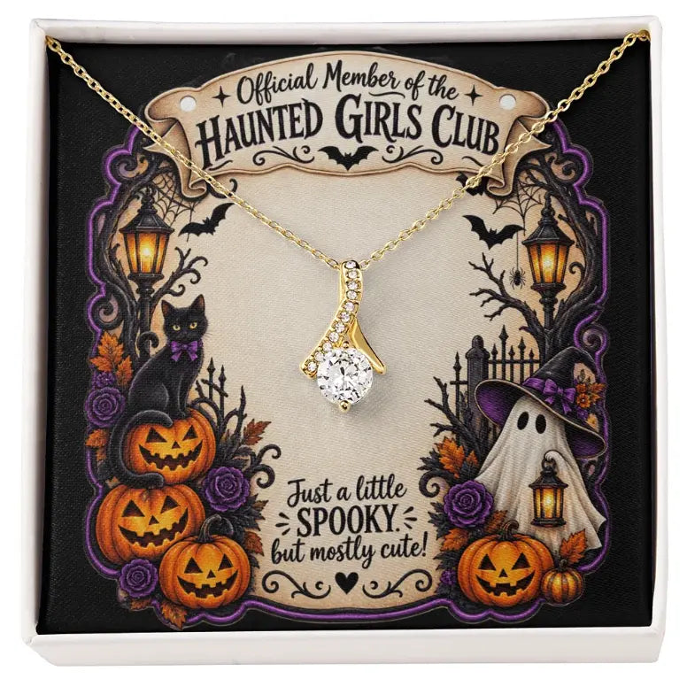 A gold necklace with a clear rhinestone pendant displayed inside a Halloween-themed gift box. The necklace is presented on a decorative backing card that reads 'Official Member of the Haunted Girls Club' and features illustrations of pumpkins, a black cat, a ghost, and bats.