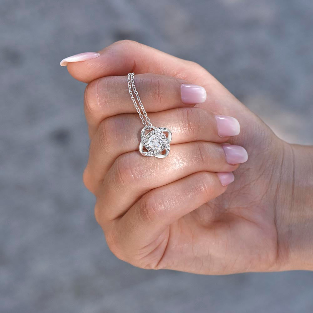 A woman's hand holding and displaying the silver-toned Necklace with clear crystal cubic zirconia in a spotlight. 