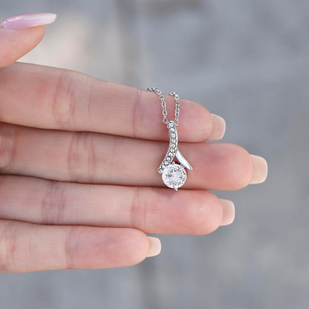 A woman's hand displaying the silver toned necklace for the "Haunted Girls Club" pendant necklace with cubic zirconia.