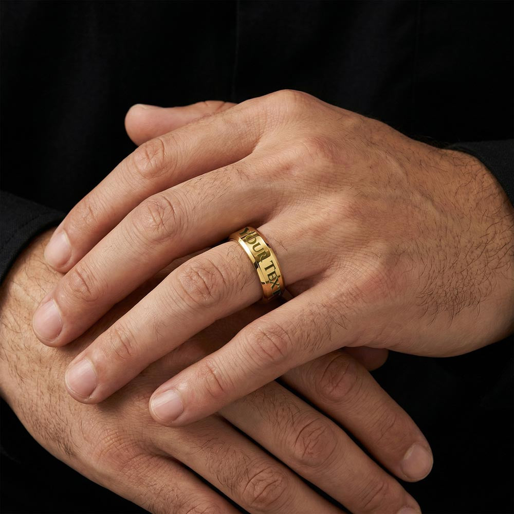 A pair of men's hands wearing a gold ring that says YOUR TEXT with a black background.